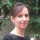 Portrait of woman with long brown hair and hazel eyes against green foliage