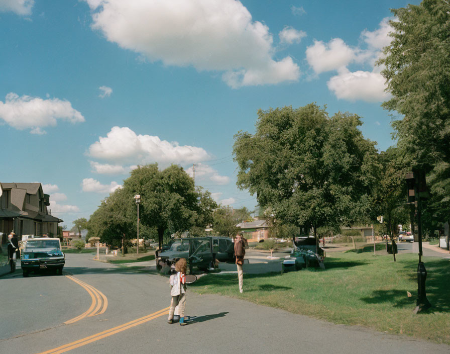 Child with skateboard crosses sunny town square among adults and parked cars