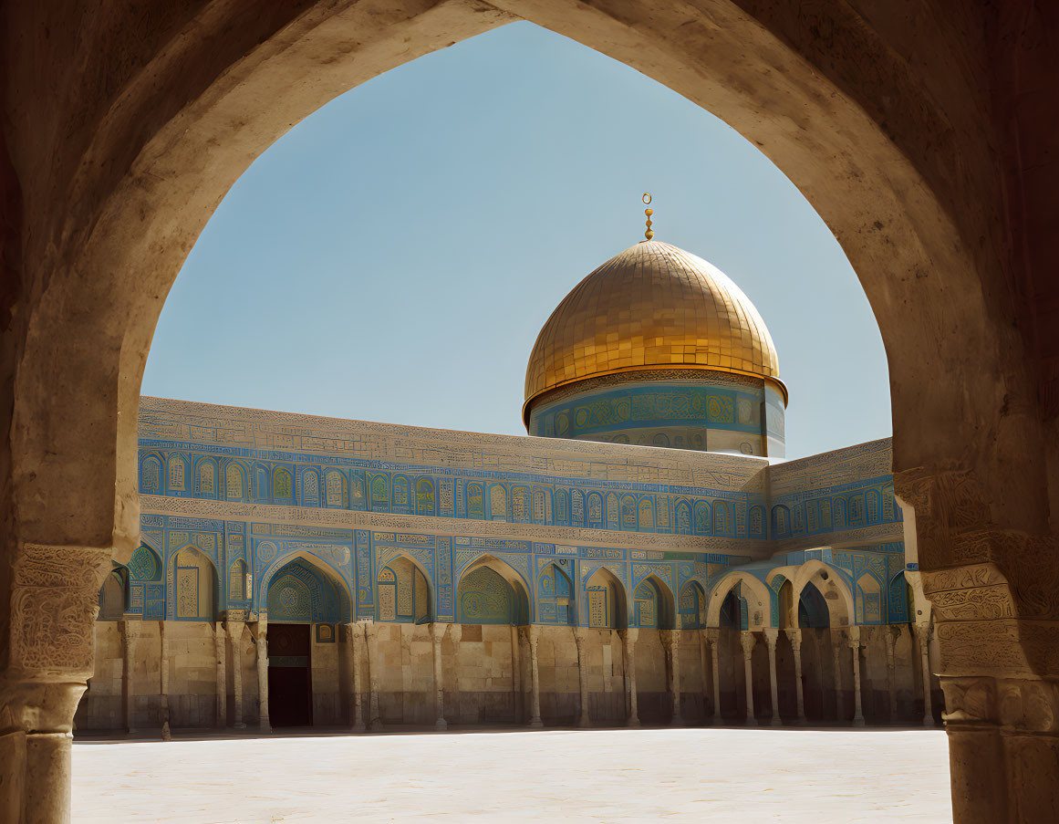 Golden-domed mosque framed by archway under clear sky