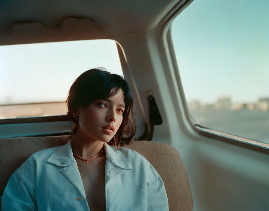 Woman with short dark hair gazes out car window at city skyline