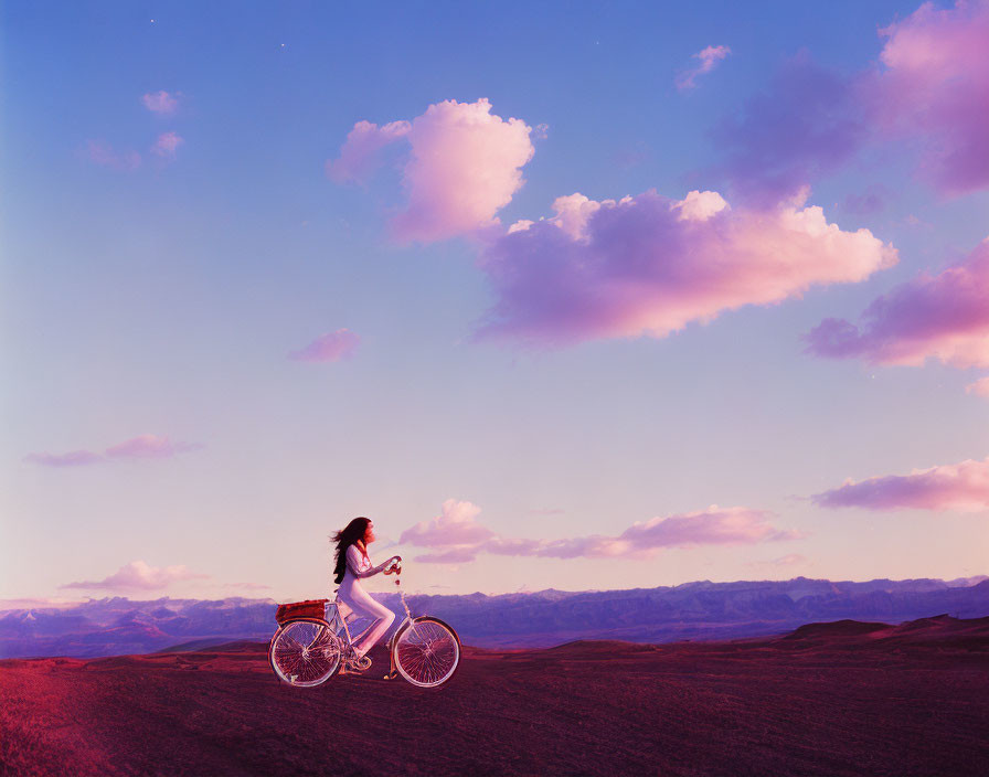 Biker on hilly terrain at dusk under purple sky