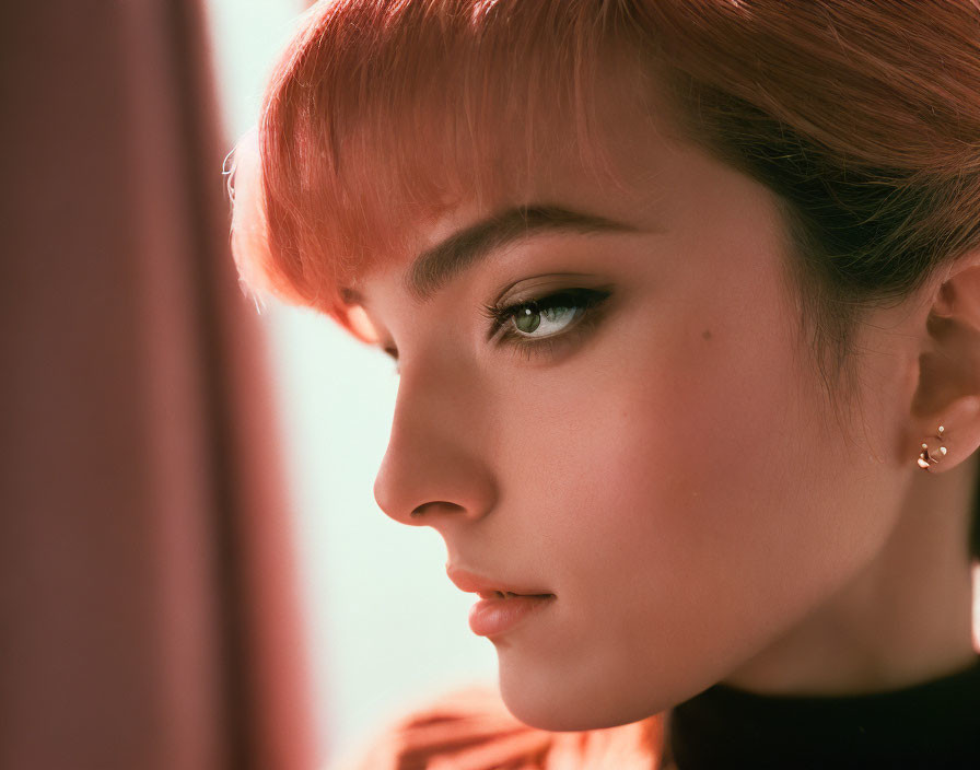 Portrait of a person with auburn hair, subtle makeup, and green eyes gazing away.