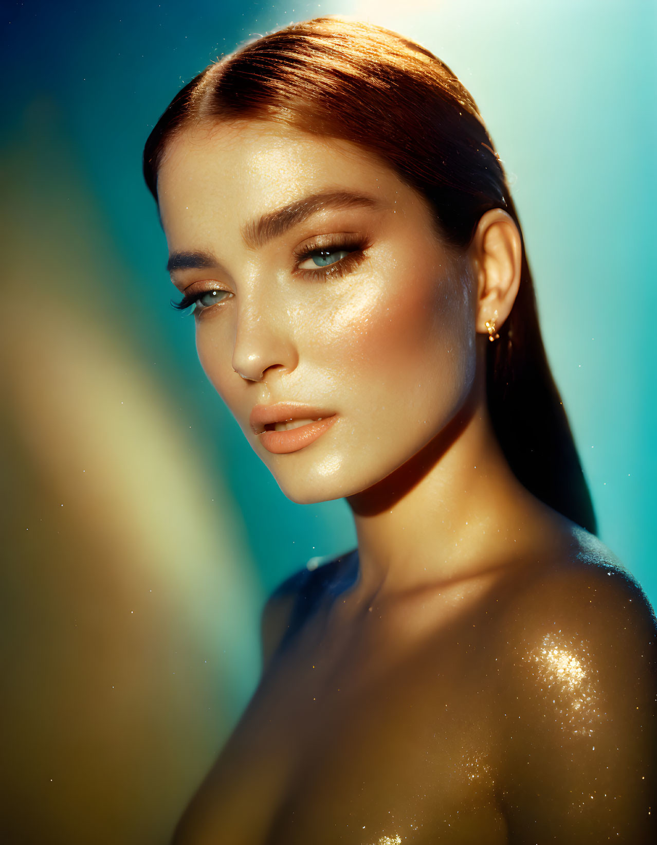 Woman portrait with glittering makeup and teal backdrop