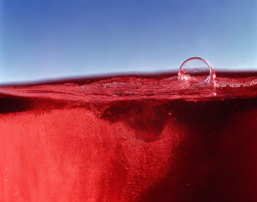 Macro Shot: Water Droplet Splash on Red Liquid Surface