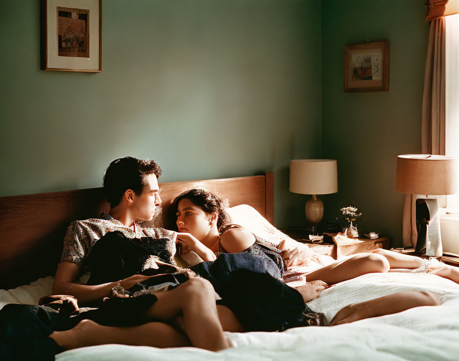 Couple lounging on bed in warm, sunlit room