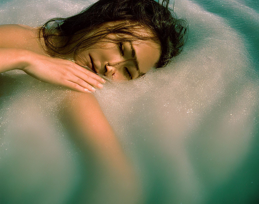 Woman in serene pose half-submerged in foamy water