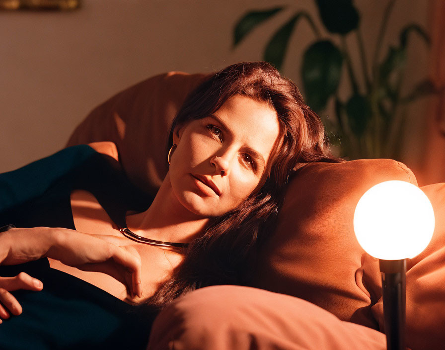 Woman reclining on sofa under warm light, evoking serene mood