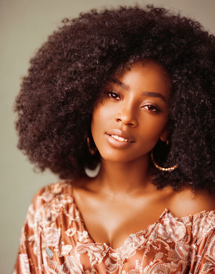 Curly-Haired Woman in Hoop Earrings and Floral Blouse on Green Background