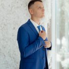 Young boy in blue suit contemplates abstract white wall art