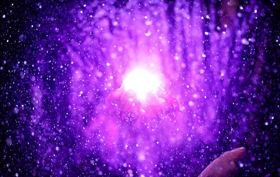 Hand reaching towards bright light orb in mystical purple haze