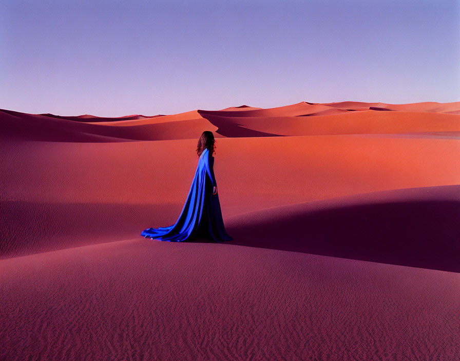 Person in Blue Cloak Stands in Desert Twilight