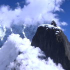 Figure sitting on snowy mountain peak under blue sky