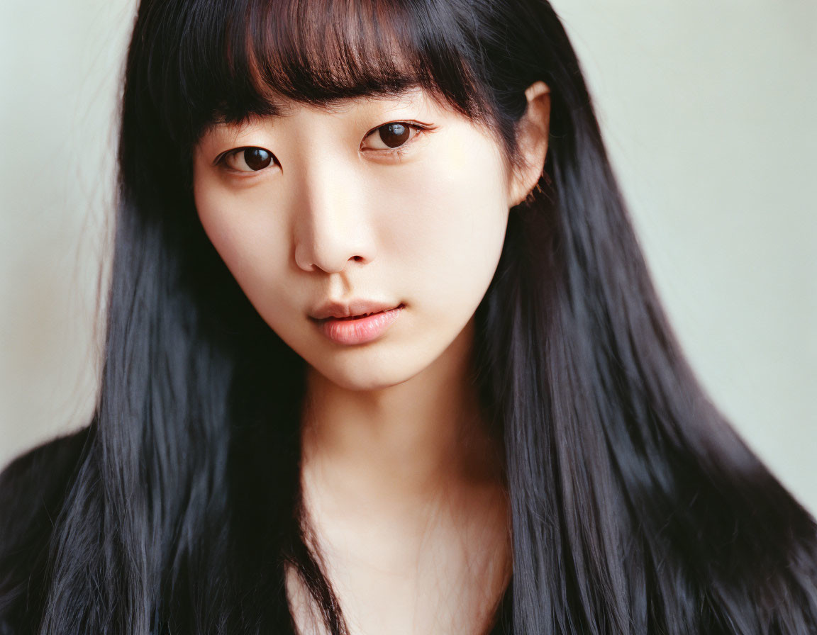 Woman portrait: Long black hair, bangs, subtle makeup, serene expression