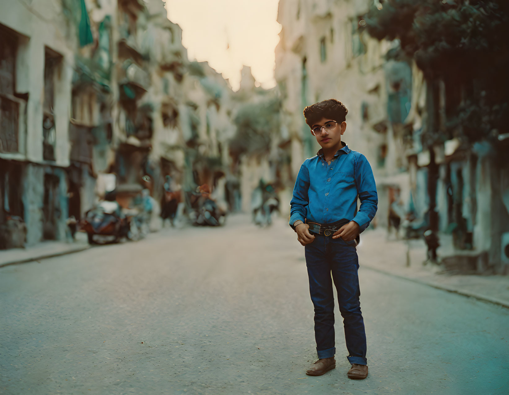 Confident young boy in narrow street with old buildings and motorcycles