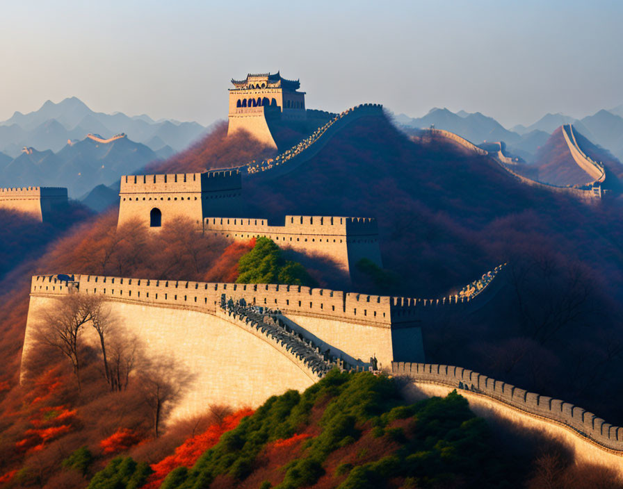 Great Wall of China winding through rugged hills with lush greenery and autumn trees under hazy sunset sky