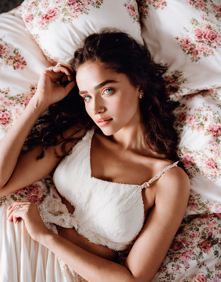 Woman with Green Eyes and Curly Hair in White Dress on Floral Bed