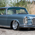 Vintage Blue Car Parked on Roadside with Clear Sky and Greenery