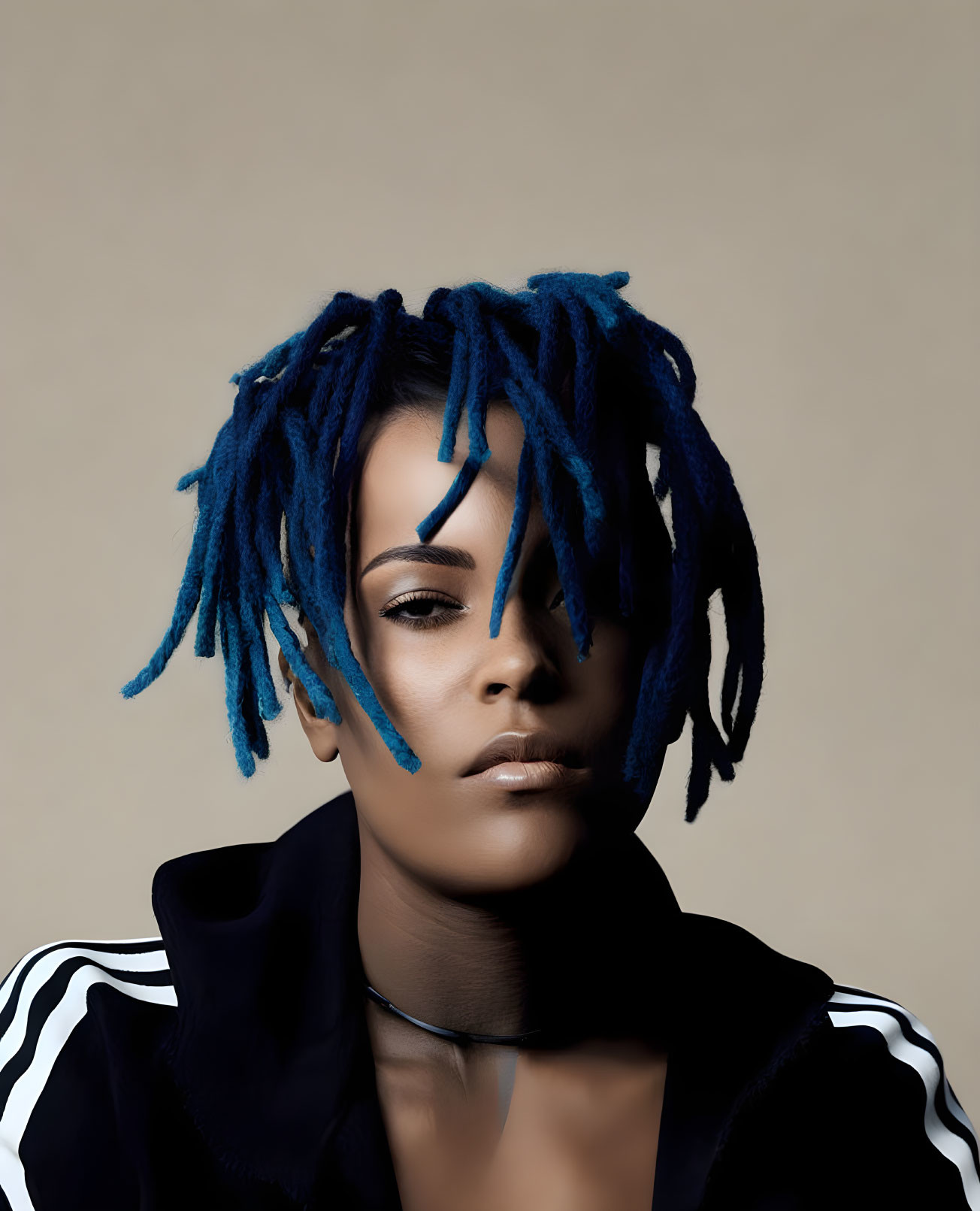 Blue dreadlocks person in black jacket on beige background