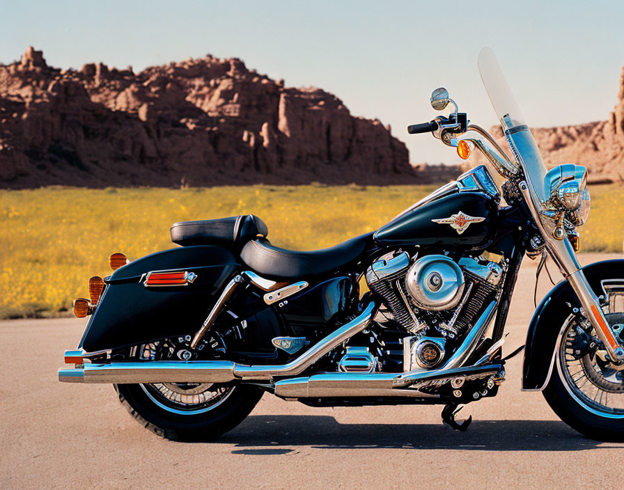 Black Motorcycle with Chrome Details Parked on Asphalt Road among Yellow Flowers and Rocky Hills