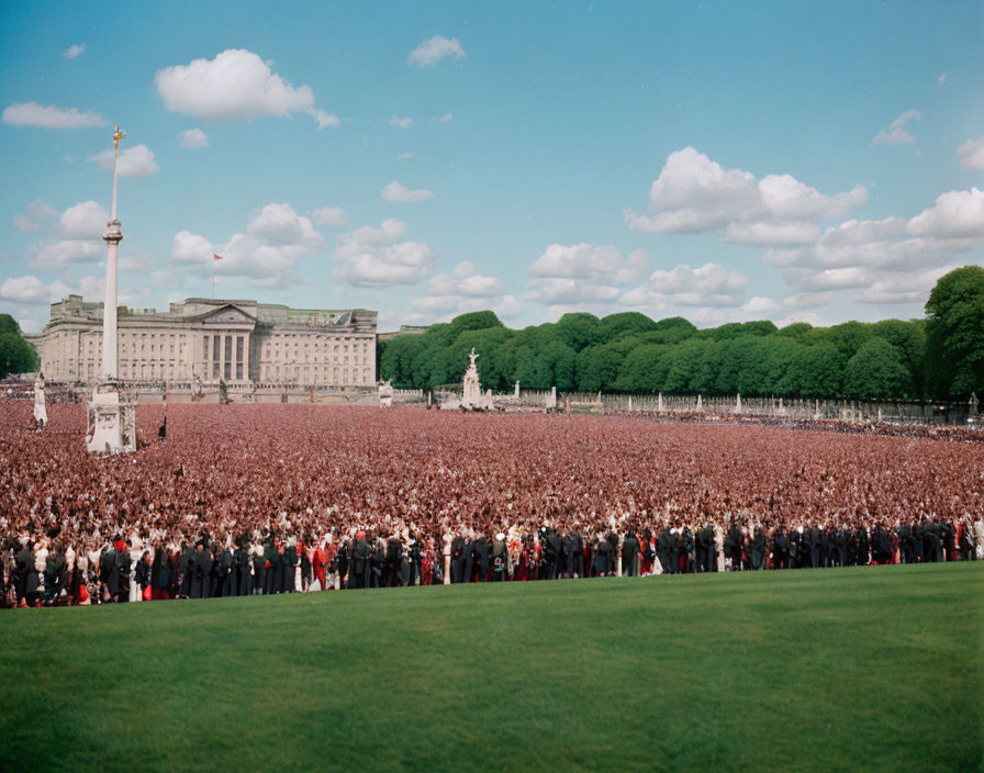 Crowd on Green Field with Stately Building, Statue, and Monument