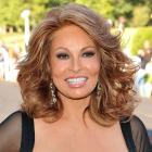 Smiling woman with auburn hair and dramatic makeup in black outfit