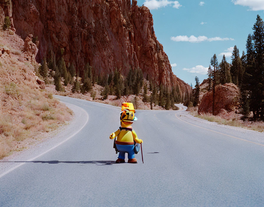 Anthropomorphic duck plush toy walking on deserted road with rocky cliffs under blue sky.