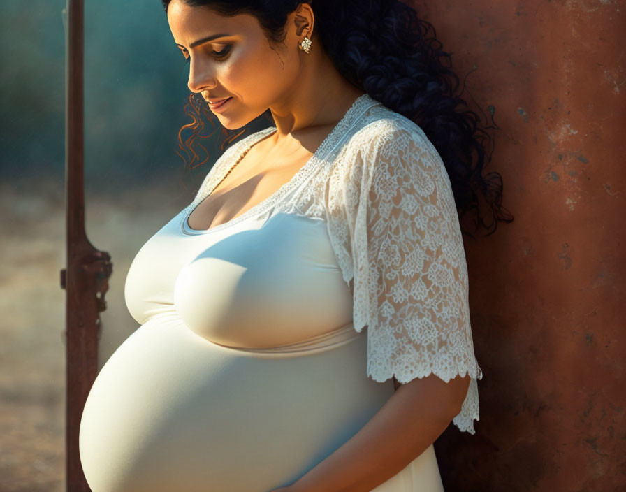 Pregnant woman in white dress and lace cardigan in golden light