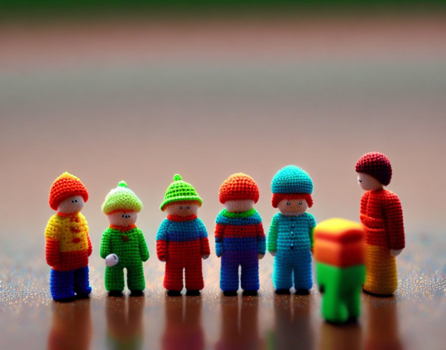 Colorful miniature knitted figures in a row, one in focus.