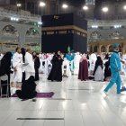 Women praying in colorful hijabs in a mosque at night with sparkling floor and illuminated minarets