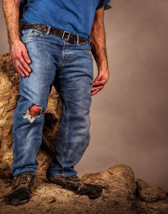 Man in Blue Shirt and Ripped Jeans Standing on Rocky Surface