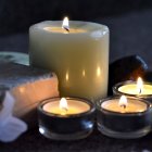 Candles, flowers, leaves, and glass jar in nature setting at dusk or dawn