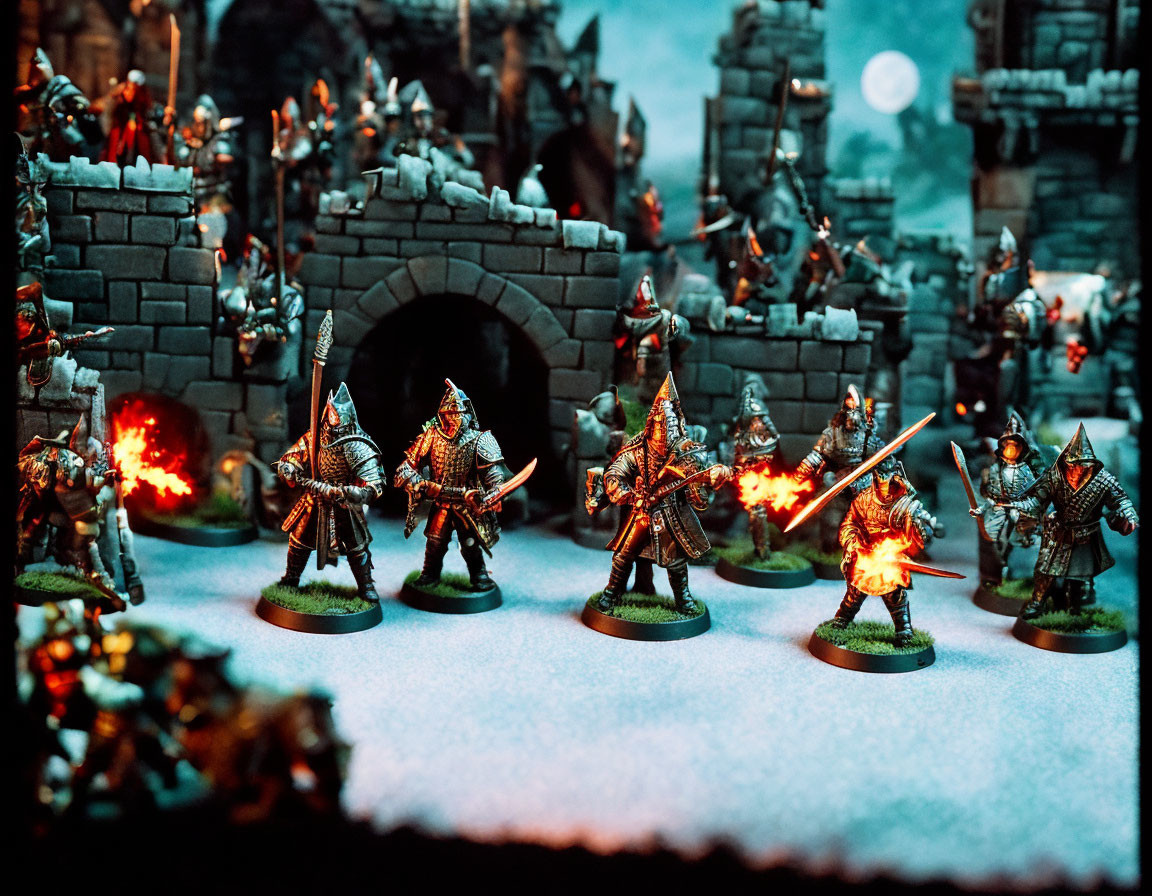 Miniature fantasy battle scene with armored warriors, castle, fire effects, moonlit sky