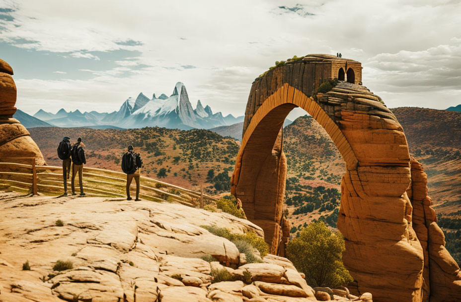 Pair admiring natural arch with person on top, distant mountains.