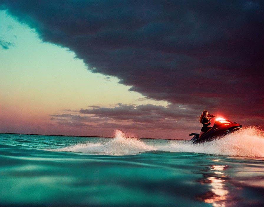 Jet ski rider speeding on water at sunset with dramatic cloudy sky