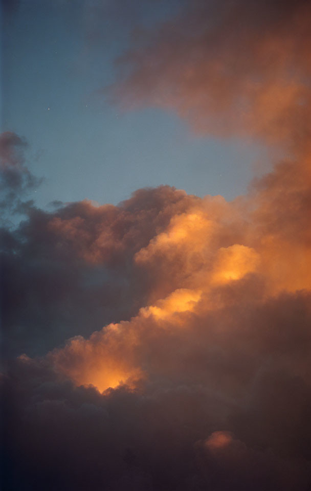 Sunset clouds in warm orange against twilight blue sky