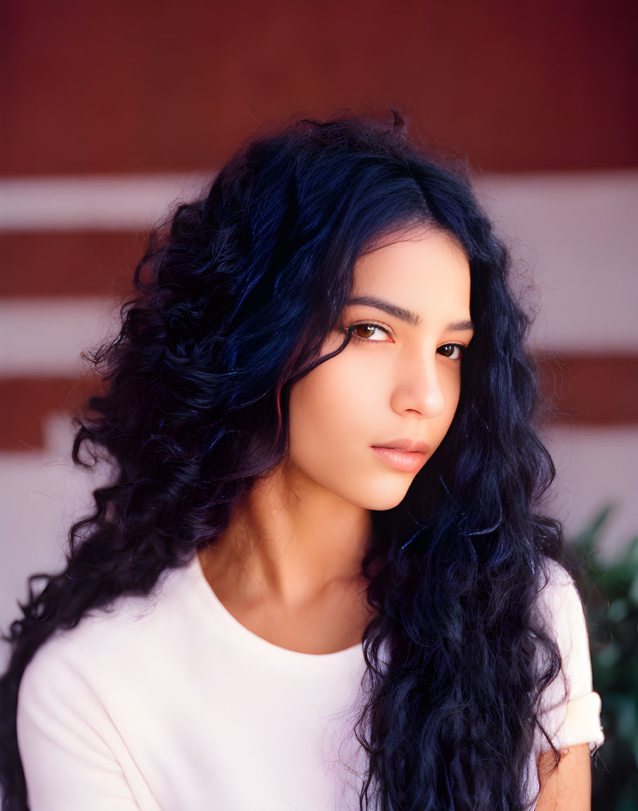 Long, Curly Black Hair Woman in White Top Against Red Brick Wall