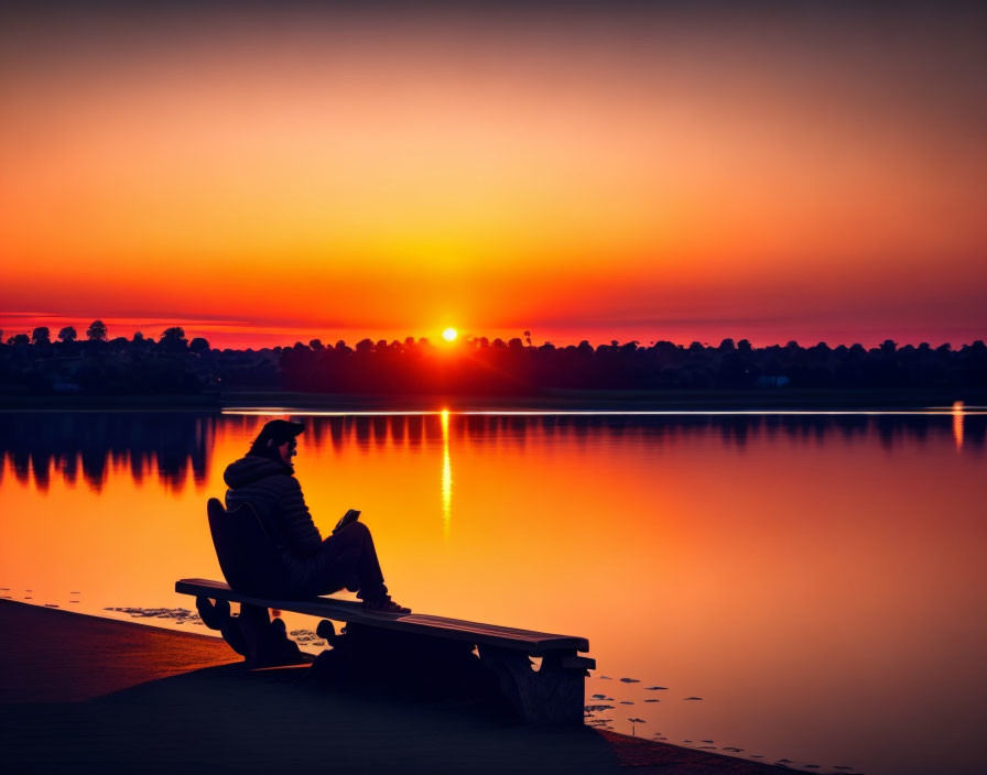 Person sitting on bench by serene lake at vibrant sunset.