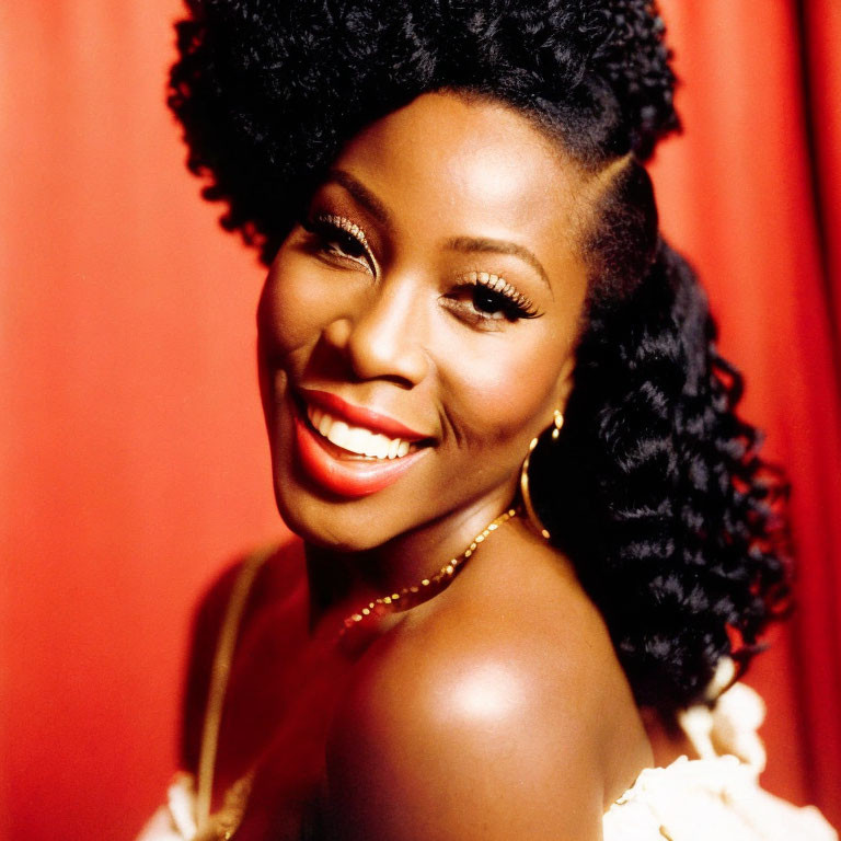 Smiling woman with curly afro and red lipstick on red background