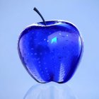 Faceted translucent blue apple on light blue background