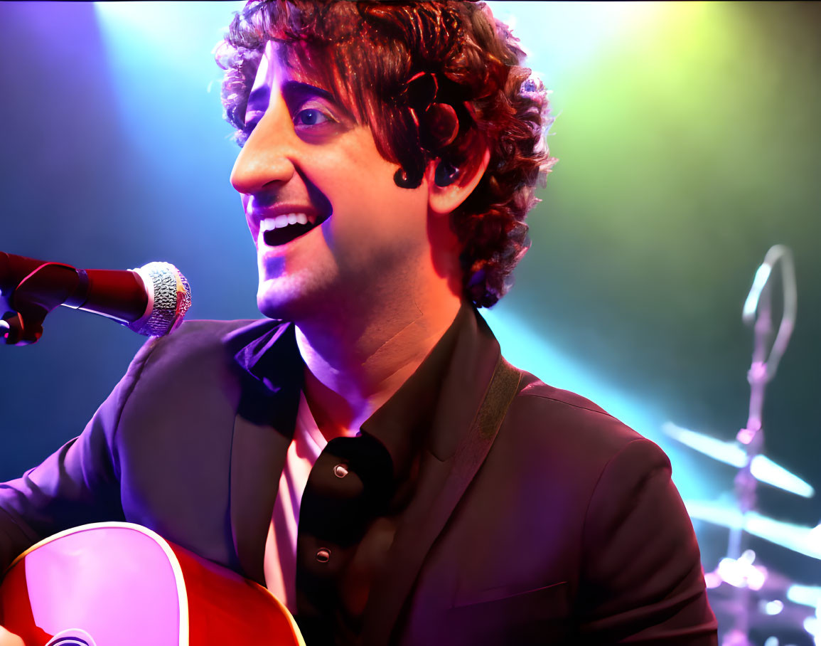 Curly-Haired Male Musician Singing and Playing Guitar on Colorful Stage