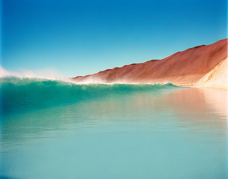 Tranquil turquoise water under clear blue sky near barren brown hillside