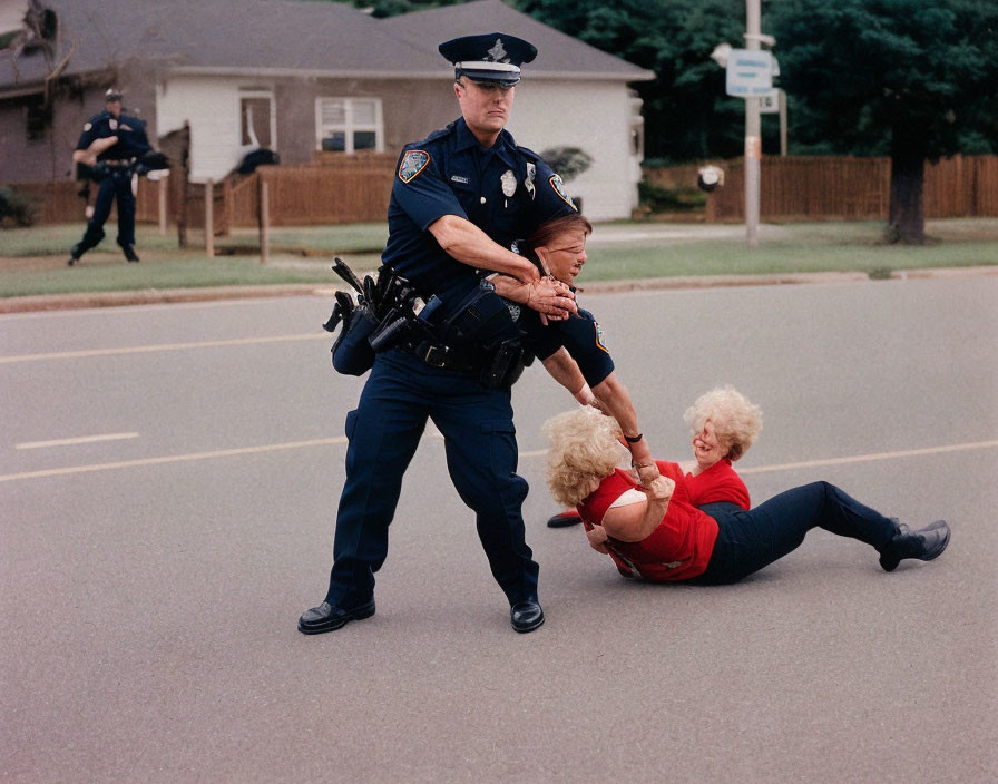 Police officers aid fallen elderly woman in suburban street