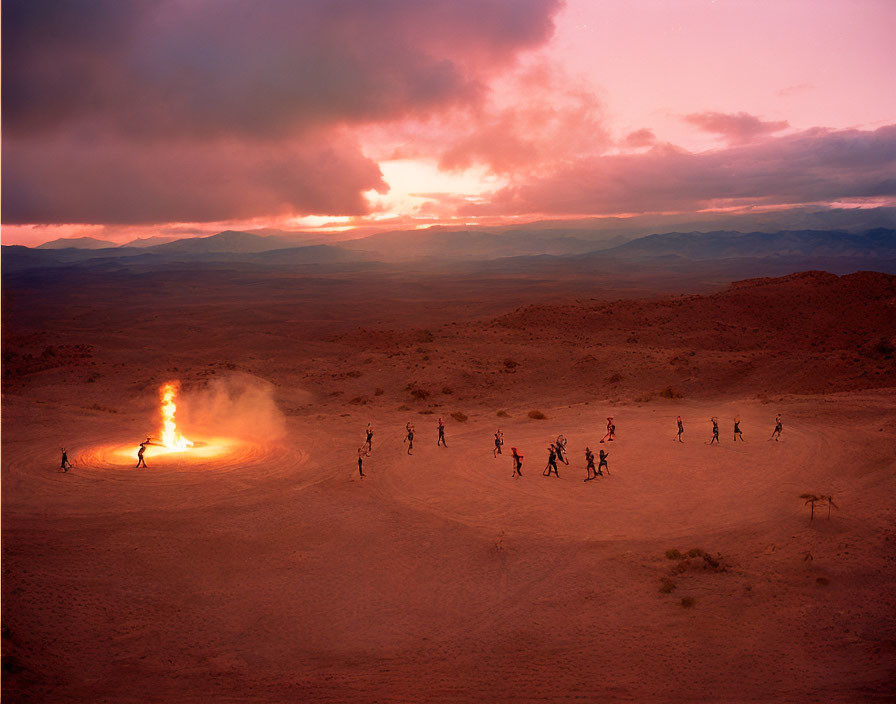 Group of People Gathered Around Large Desert Fire at Dusk