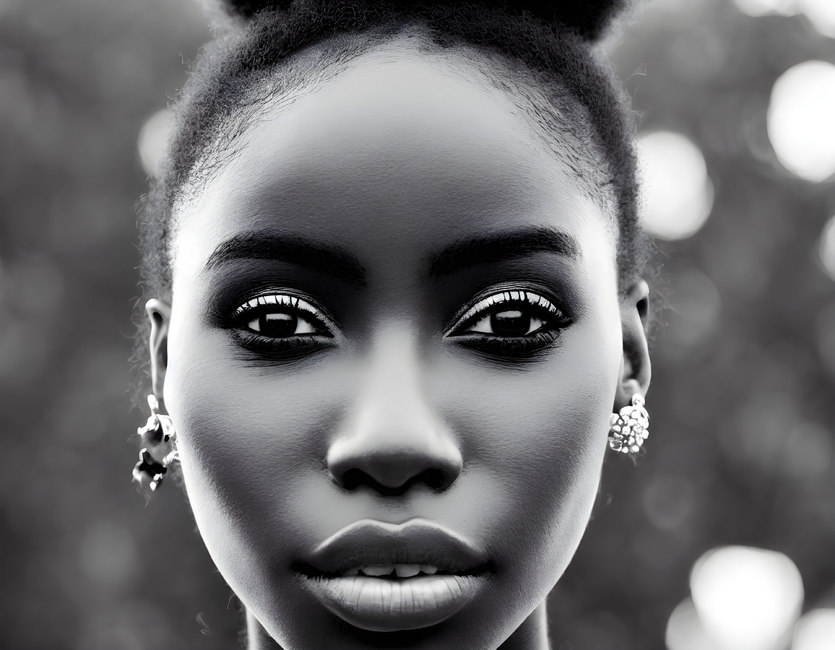 Woman with striking eyes and earrings in close-up black and white photo