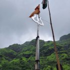 Tall Lord Shiva statue with trident and drum in lush green setting