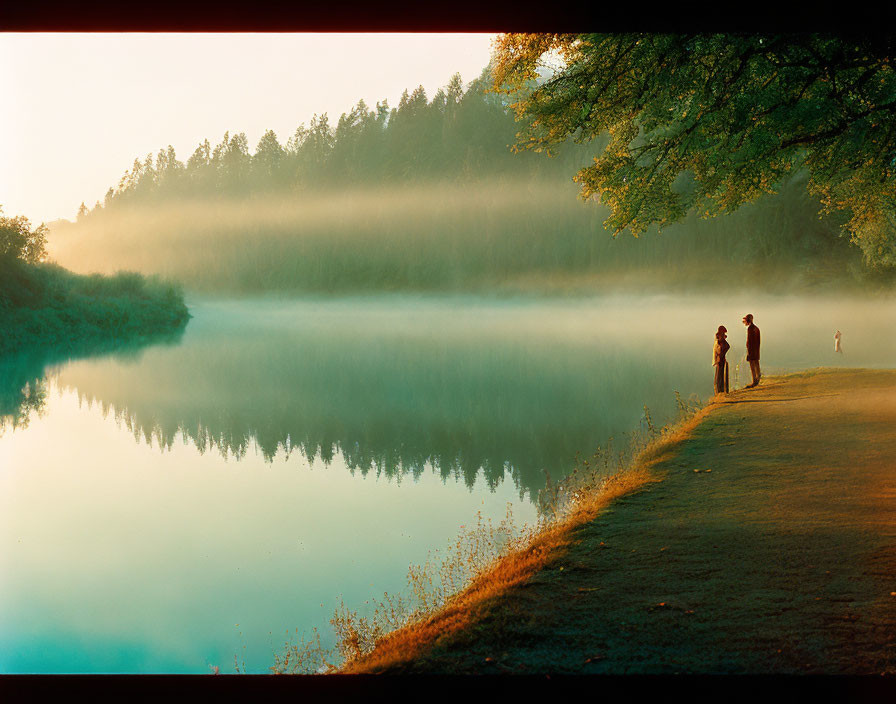 Tranquil dawn scene: misty lakeside, silhouettes of people, lush trees,