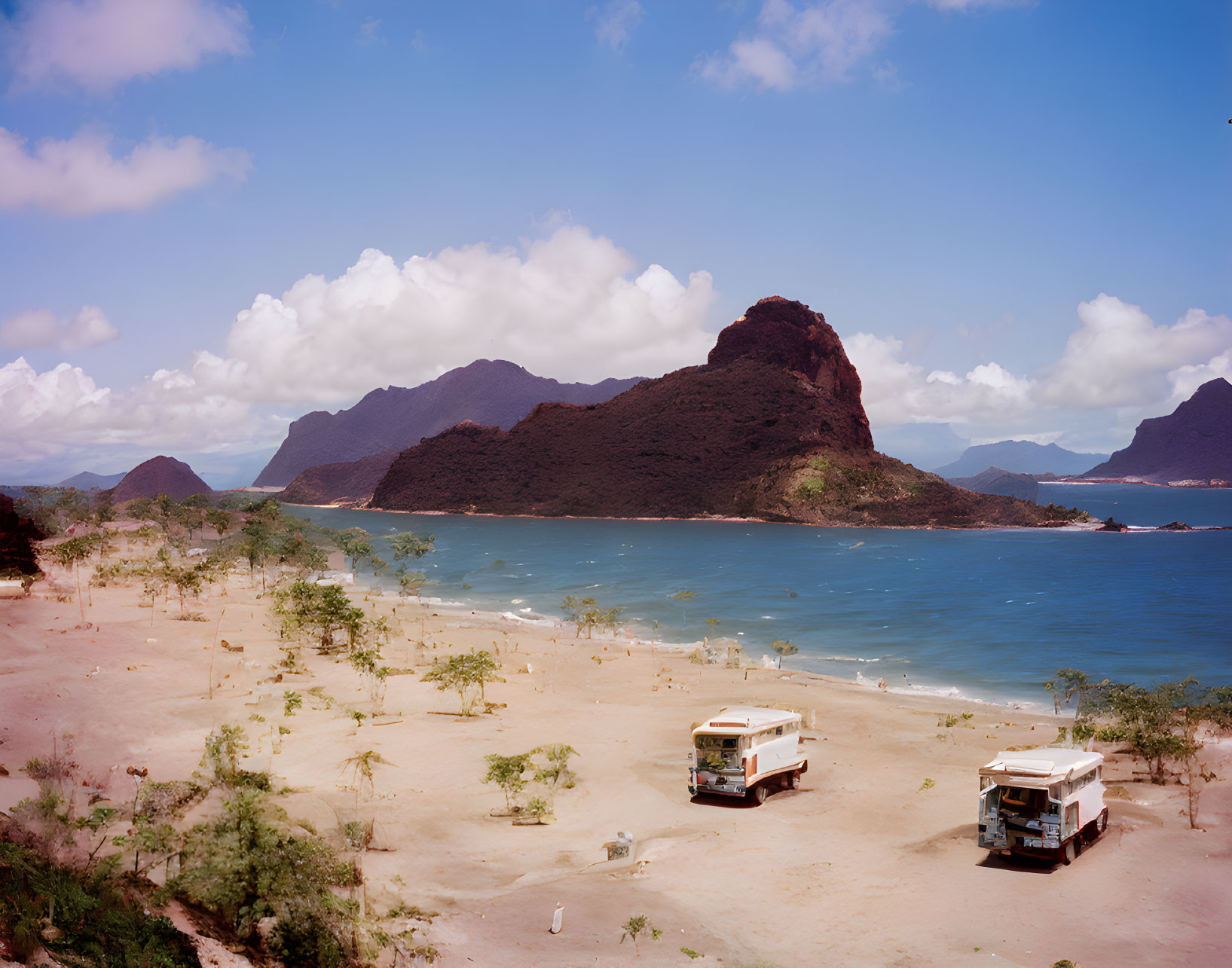 Vintage Vans Parked on Tranquil Beach with Mountains