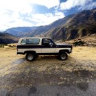 Vintage Camper Van on Desert Trail with Rocky Hills and Cloudy Sky