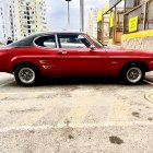 Vintage Red Coupe Parked on Dusty Street with Traditional Buildings