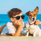 Boy with sunglasses and dog on sunny beach gaze into distance